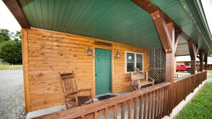A wooden cabin with a green door, a bench, and a sign that reads "Welcome to our cabin." - 1/2 double cabin with king bed and single child sized pull-out sleep sofa (sleeps 2 adults & 1 child (Flintstone)