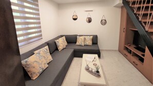 Una sala de estar moderna con un sofá seccional gris oscuro, una mesa de centro blanca y una escalera con barandillas de madera.