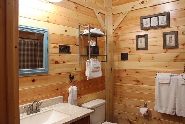 A wooden cabin bathroom with a sink, toilet, and towel rack.