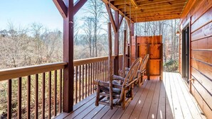 Eine Holzterrasse mit Geländer, einer Schaukel und einer Bank.