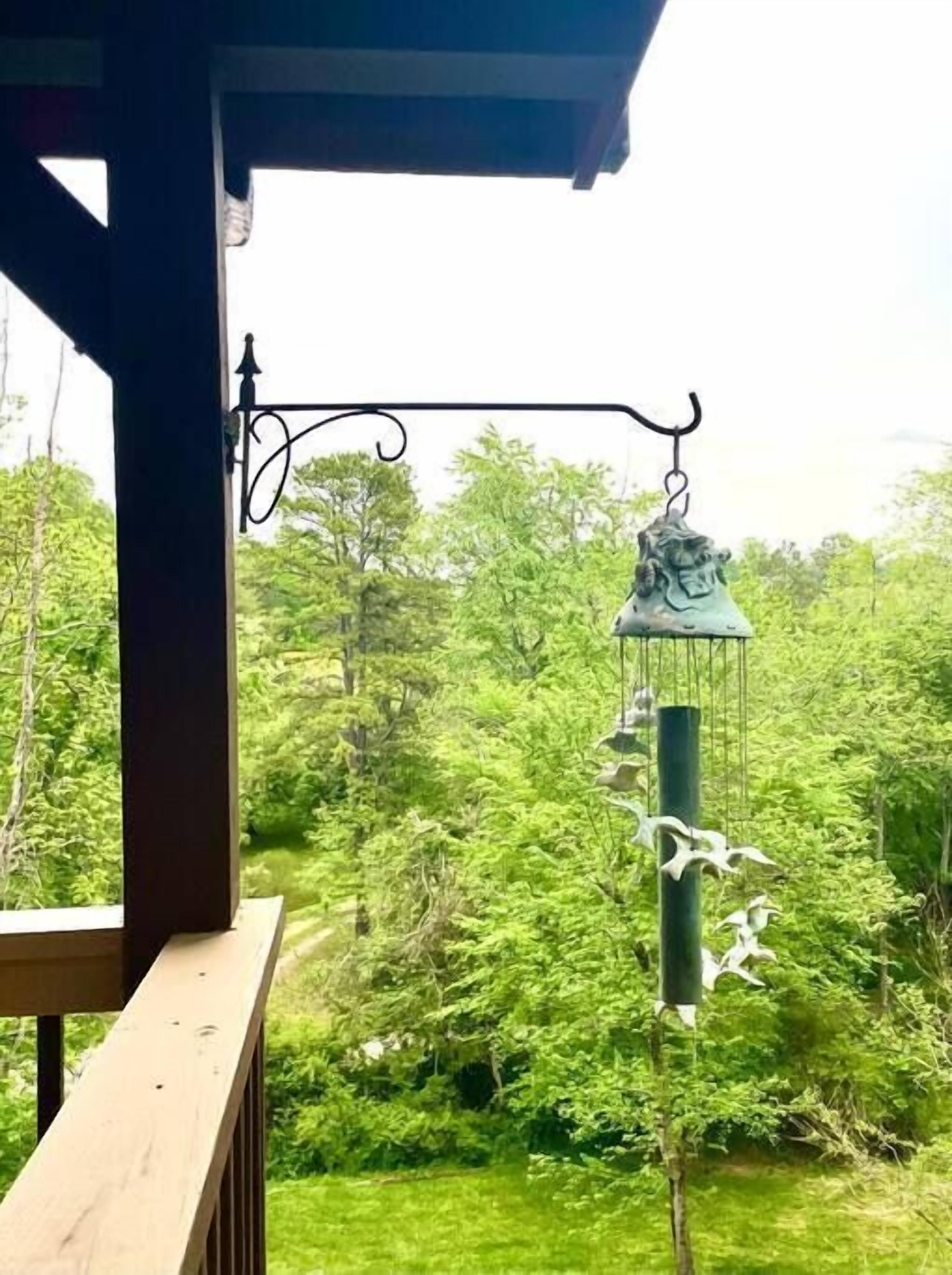 Eine Holzterrasse mit einem hängenden Windspiel.