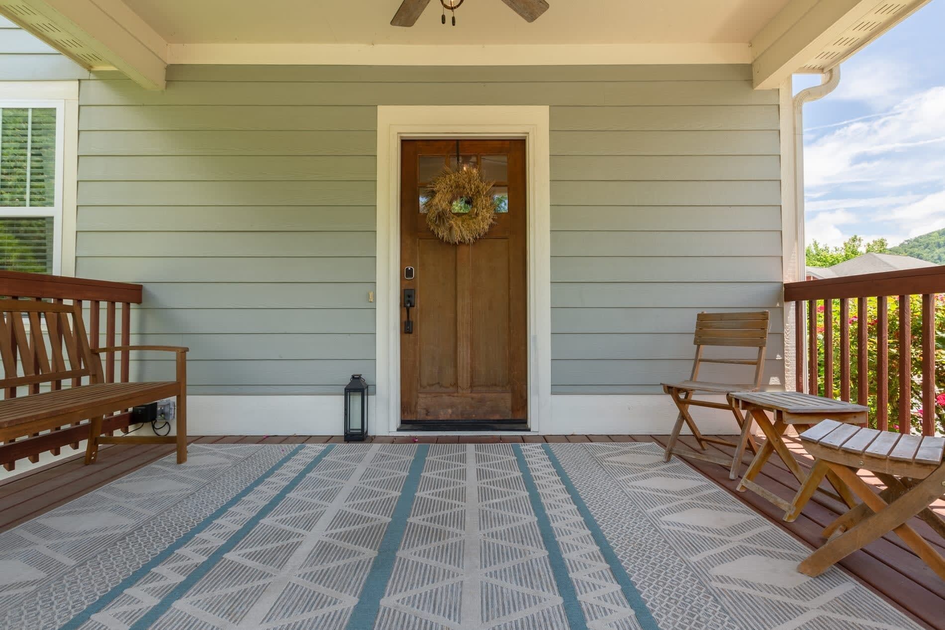 A porch with a wooden door, two wooden benches, and a patterned rug.