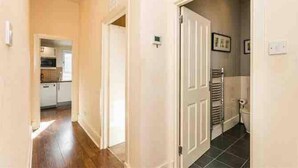 Un pasillo con piso de madera que conduce a una zona de cocina con armarios y un microondas.