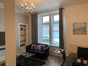 Relax in this stylish living room with a sofa, coffee table, side table, and mounted TV.