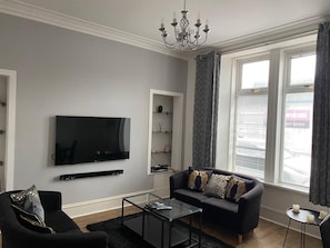 Relax in this stylish living room with a flat-screen TV, comfortable sofa, and glass coffee table.