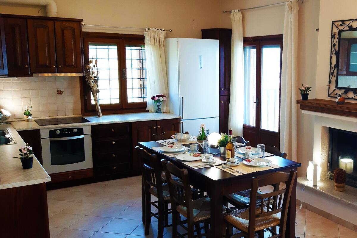 Una cocina con armarios de madera, una mesa de comedor para cuatro personas y una chimenea.