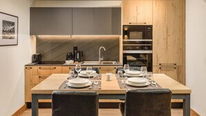 Una cocina moderna con armarios de madera, un microondas integrado y un comedor preparado para cuatro.