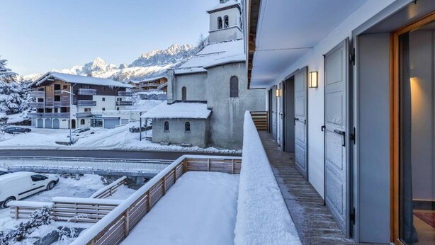 Un balcón cubierto de nieve con vistas a una montaña e iglesia.