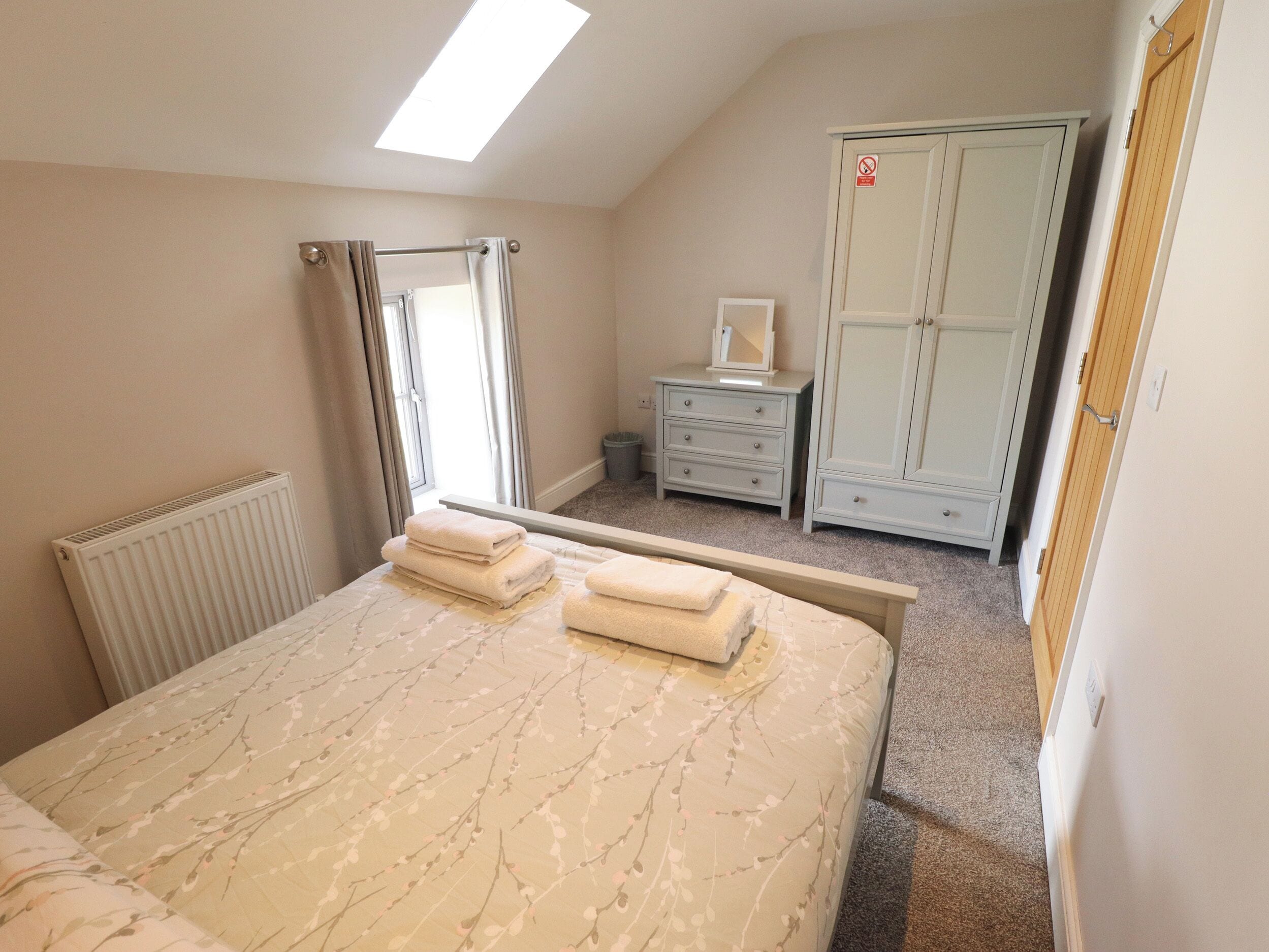 A bedroom with a bed, a dresser, a wardrobe, and a radiator.
