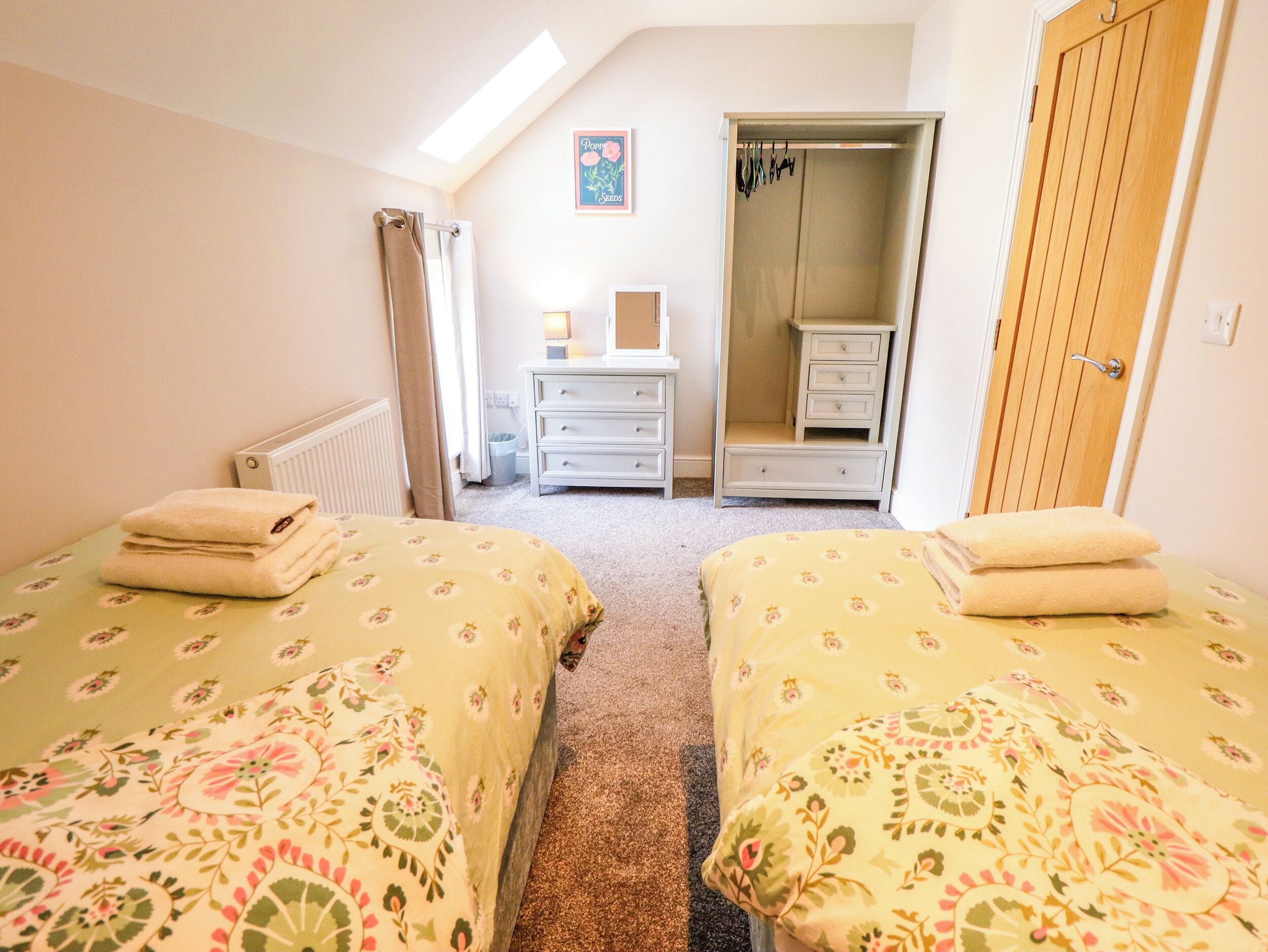 A bedroom with two beds, a dresser, a mirror, and a wardrobe.