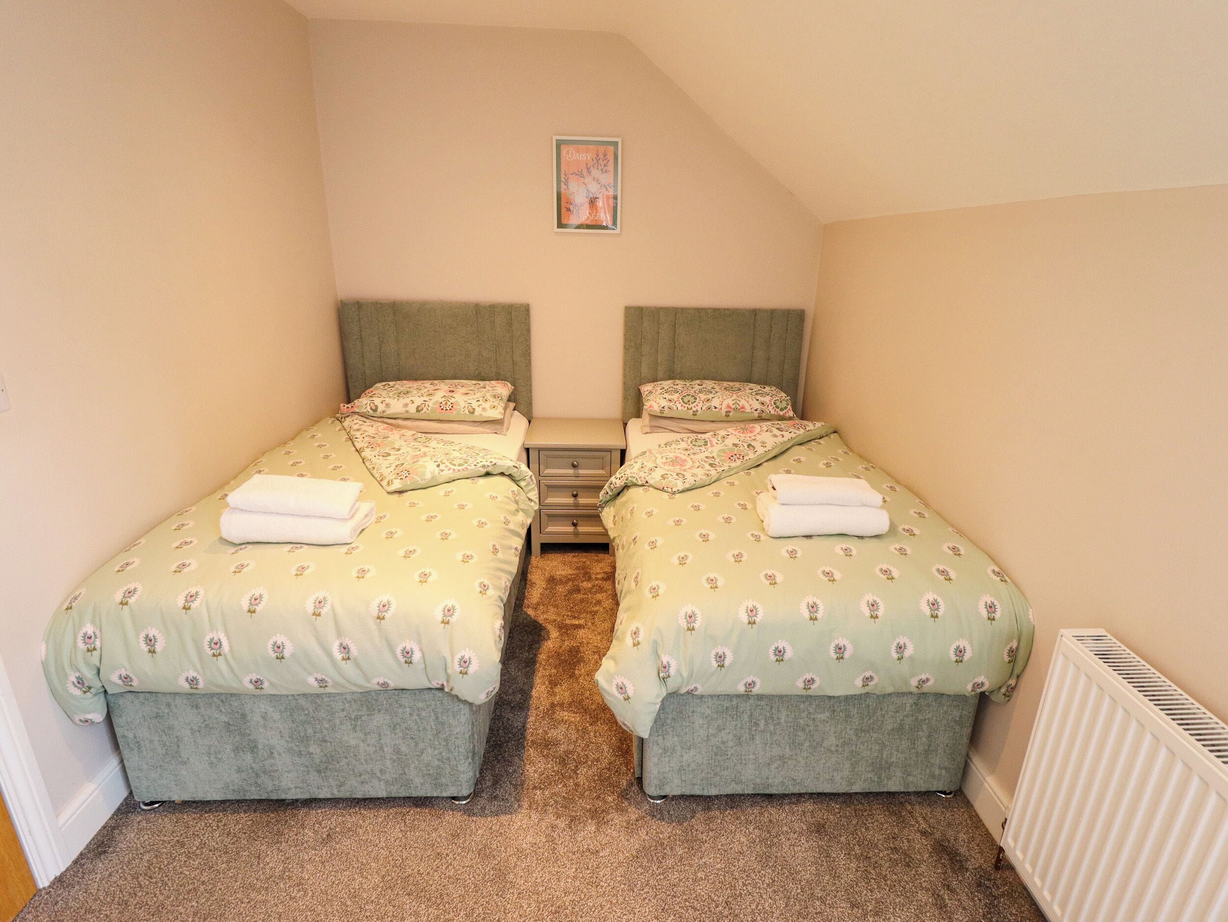 A twin room with two beds, a bedside table, and a radiator.