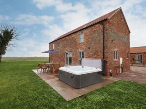 A brick house with a hot tub, patio furniture, and a grassy yard. - Acacia Barn (Boston)