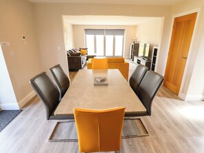 A modern dining area with a rectangular table, black and yellow chairs, and a sofa in the background. - Acacia Barn (Boston)