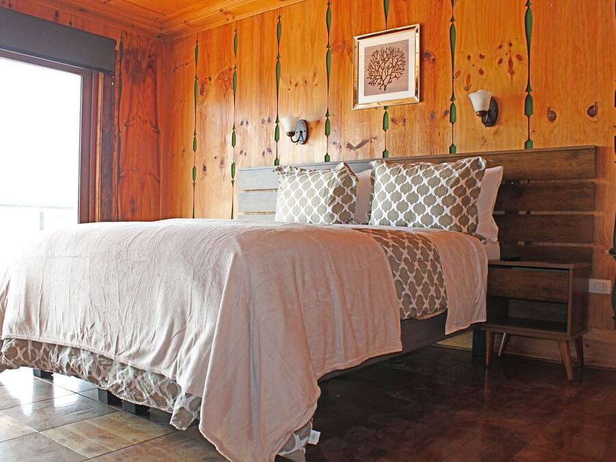 Une chambre à coucher aux murs lambrés, avec un lit, une table de chevet et un tableau encadré.