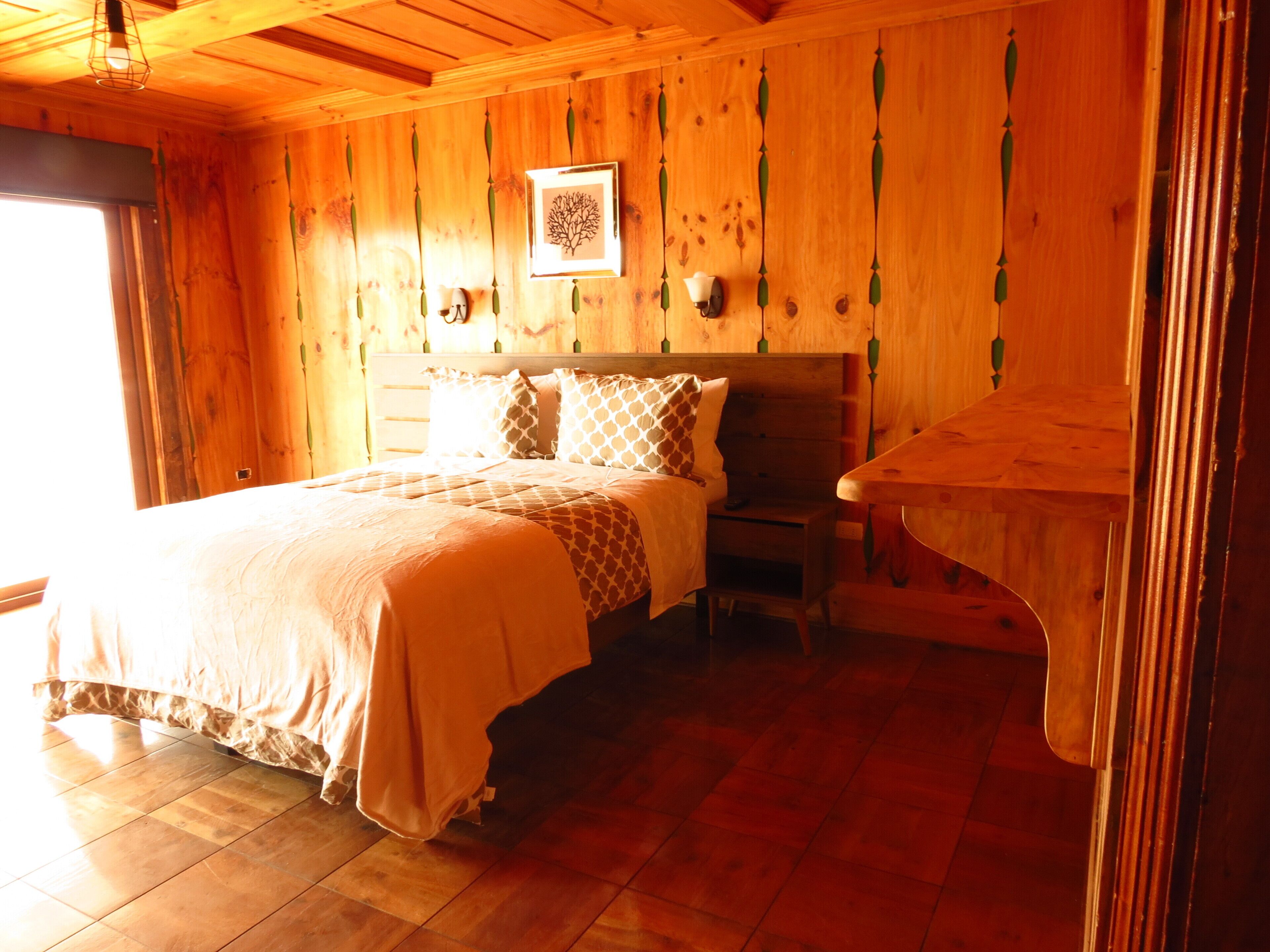Une pièce en bois avec un lit, une table de chevet et une table.