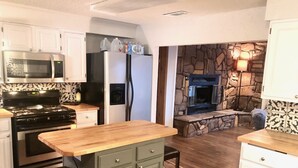 A modern kitchen with a central island, built-in appliances, and a stone fireplace. - Charming cozy lake cabin, 300 yds from Lake Texoma beach, fishing, boat ramp! (Pottsboro)