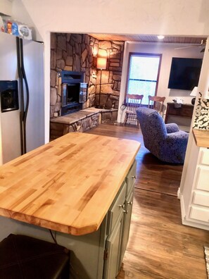 A kitchen with a wooden countertop, stone wall, and a stone fireplace. - Charming cozy lake cabin, 300 yds from Lake Texoma beach, fishing, boat ramp! (Pottsboro)