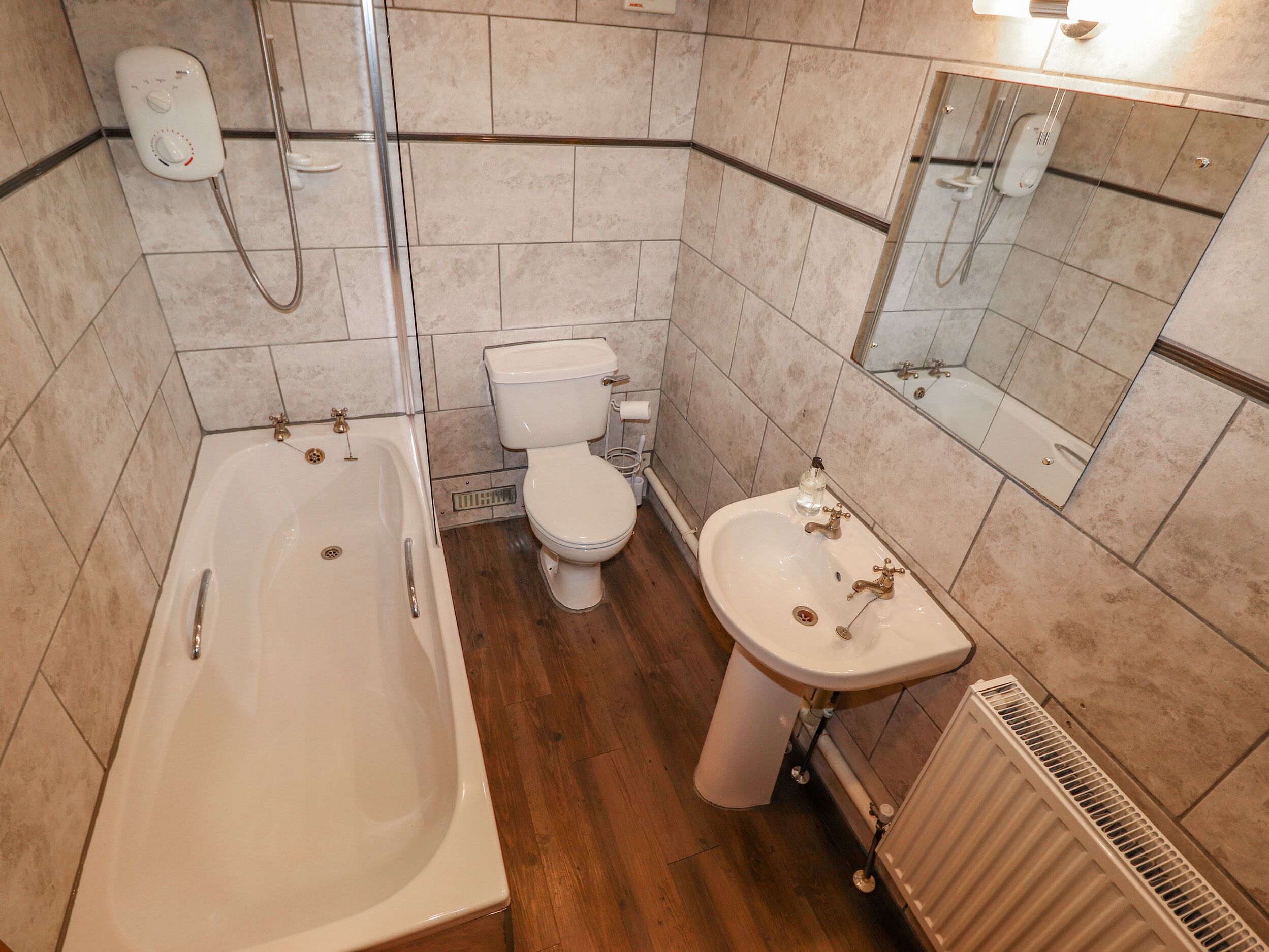 Une salle de bain équipée d’une baignoire, de toilettes, d’un lavabo et d’un miroir.