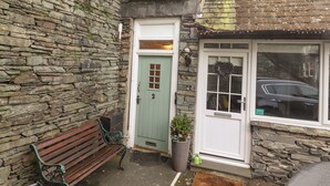 A stone building with a green door, a bench, and a potted plant.