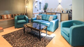 A modern living room with teal sofas, a glass coffee table, and a patterned rug.