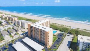 A coastal hotel with multiple floors, a parking lot, and a view of the beach and ocean. - Oceanfront walkout stunning condo! (Cape Canaveral)