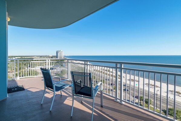 Enjoy the ocean view from this balcony with two chairs and a table.
