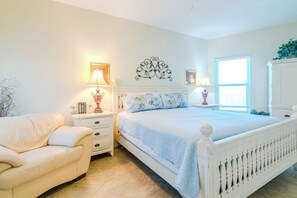 Relax in this serene bedroom with a large bed, nightstand, and comfortable armchair.