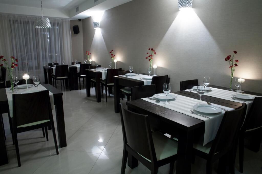 A dining area with multiple tables set for dining, each with white tablecloths and candles.