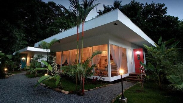 A modern house with a glass extension, surrounded by lush greenery. - Casa Blanca Villas Ojochal (Ciudad Cortés)