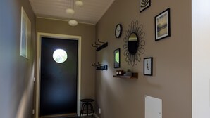 Ein Flur mit einer runden Tür, einem kleinen Hocker, einem an der Wand befestigten Regal mit Dekoration und einer Uhr.