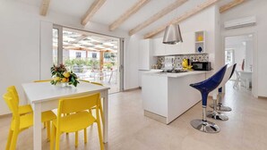Une cuisine moderne avec un îlot central, des chaises jaunes et un tabouret de bar bleu.