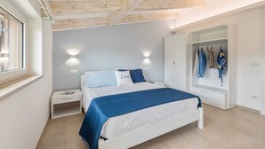 Une chambre à coucher avec un lit, des tables de chevet, une armoire et une fenêtre.