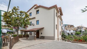Un bâtiment à deux étages doté d’un patio couvert et d’un petit jardin.
