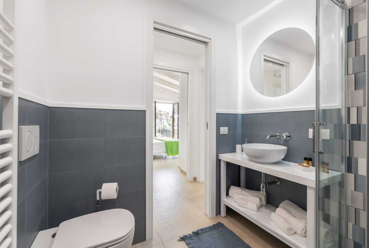 A modern bathroom with a white toilet, a large sink with a mirror, and a glass shower enclosure.