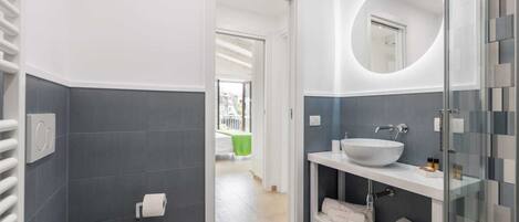 A modern bathroom with a white toilet, a large sink with a mirror, and a glass shower enclosure.