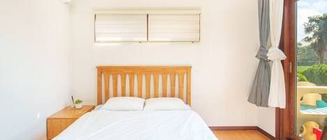 A bedroom with a wooden bed, a nightstand, a window with curtains, and a ceiling fan.