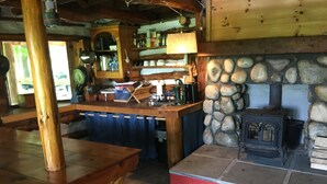 Ein rustikales Interieur mit Kamin aus Stein, Holzmöbeln und einer Bar.