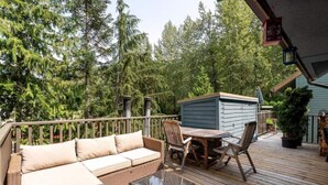 A wooden deck with a sofa, chairs, and a table. - Lux Townhome in the Trees - Walk to lifts! (Whistler)