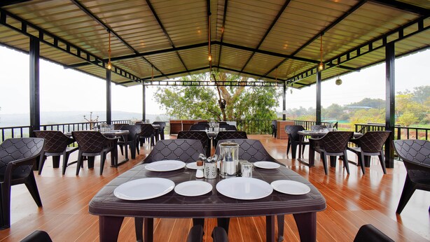 Un espace de restauration en plein air, avec des tables et des chaises, offrant une vue sur le paysage et doté d’une structure de toit abritée.