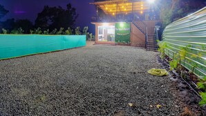 Un bâtiment sur lequel on peut lire, sur une enseigne, les mots « The Appa's Resort », pris de nuit. On y voit un sol recouvert de gravier, une clôture verte et un escalier menant à un étage supérieur.