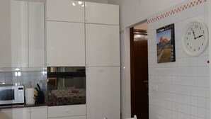 Una cocina con armarios blancos, microondas y una mesa de comedor con sillas rojas.