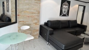A modern living room with a sectional sofa, a glass table, and a brick accent wall.
