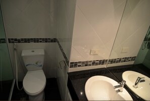 A bathroom with a toilet, sink, and tiled walls.