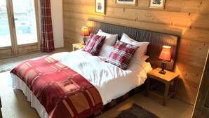 A cozy bedroom with a large bed, two bedside tables with lamps, a wooden headboard, and a window with curtains. - Sainte Foy Self-Catered Ski Apartment (Sainte Foy Tarentaise Station)