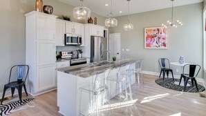 A modern kitchen with white cabinets, stainless steel appliances, and a central island with bar stools.