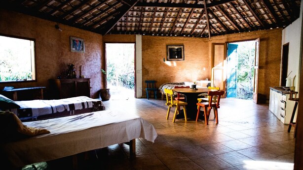 A room with a bed, a table, chairs, and a kitchen area. - Pousada Saúde Melhor (Extrema)