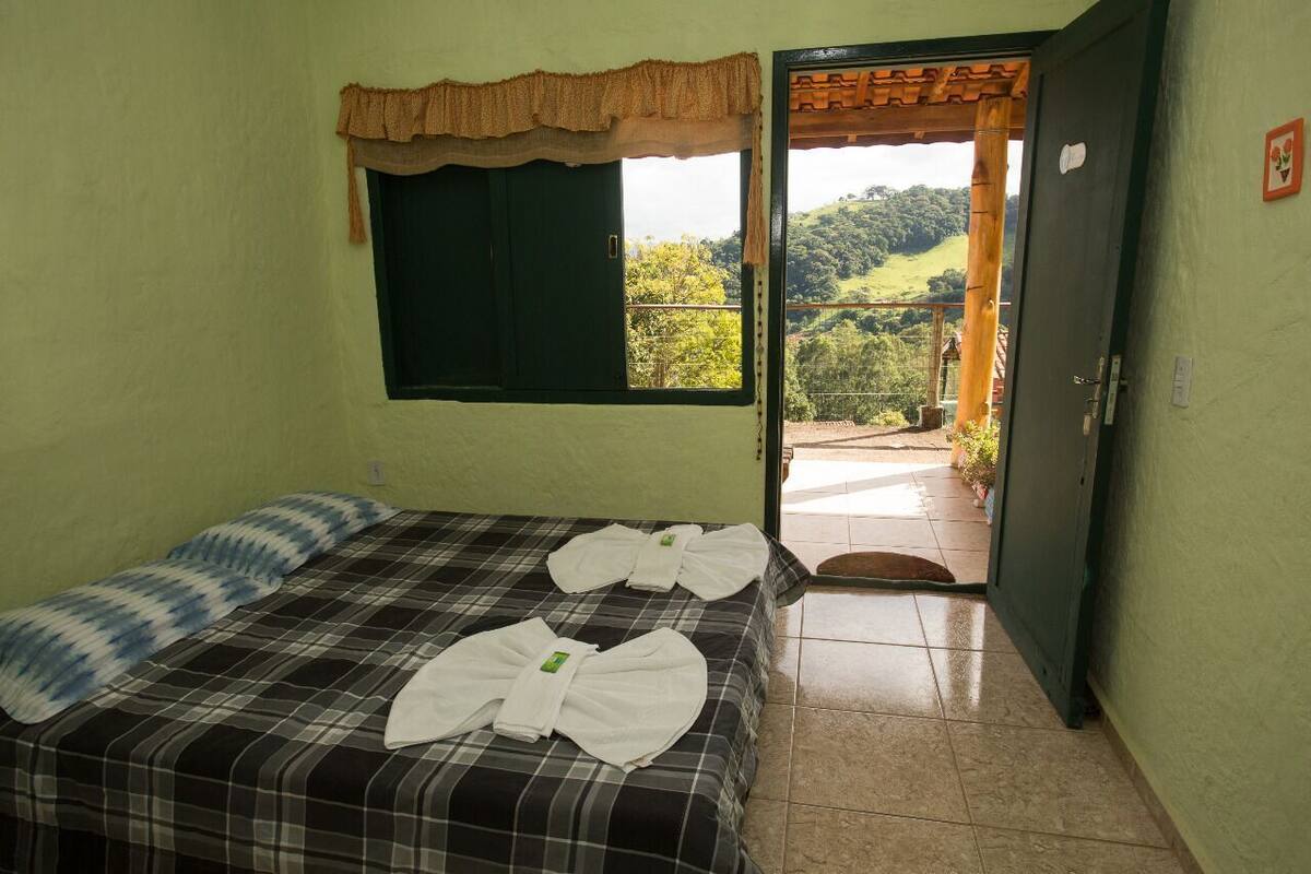 A room with a bed, a window with a curtain, and a door leading to an outdoor area.