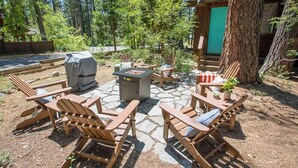 A wooden deck with Adirondack chairs, a fire pit, and a covered grill area. - Clean & Cozy. Walk to 3 beaches. Dog friendly. (Tahoe City)