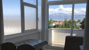 A balcony with a table and chairs, a sofa, and a view of buildings and mountains.