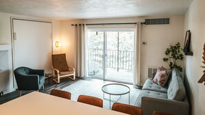 A modern living room with a sofa, armchairs, a dining table, and a balcony with a view. - Riverfront Condo 2 blocks to downtown Bend (Bend)